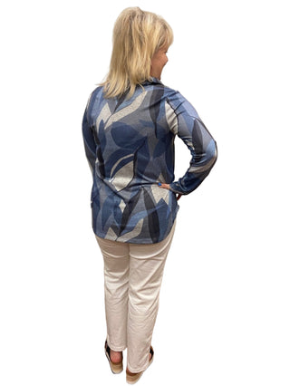 Person wearing a blue patterned top and white pants in a fitting room.