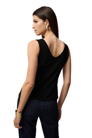 Woman wearing a black sleeveless top and dark pants on a light gray background