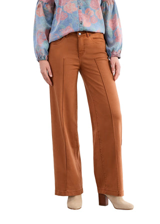 Person wearing brown pants and a patterned shirt against a white background