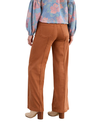 Person wearing brown pants and a colorful floral blouse against a white background
