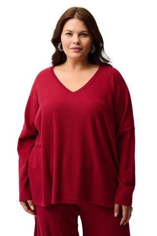 Woman wearing a red sweater and pants against a white background