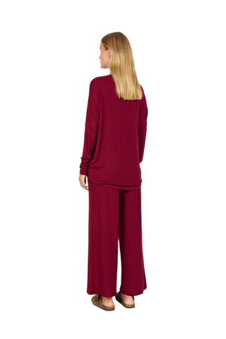 Woman wearing a burgundy outfit with wide-leg pants on a white background