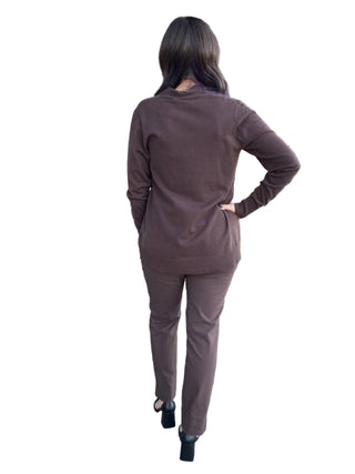 Person in a brown outfit standing outside a building with decorative plants and 'ANNE'S' sign.