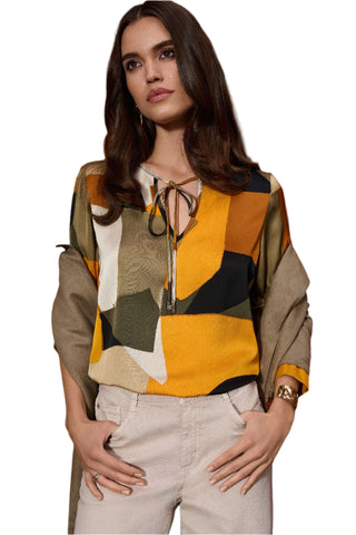 Woman wearing a colorful geometric-patterned blouse against a brown background