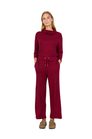 Woman wearing a burgundy jumpsuit against a white background