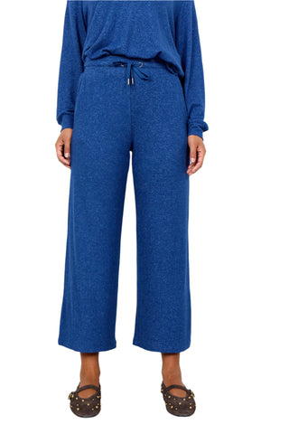 Person wearing a blue outfit with wide-leg pants against a white background