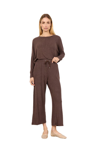 Woman wearing a brown outfit with wide-leg pants against a white background