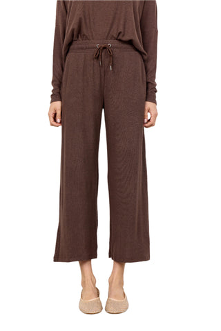 Person wearing a brown outfit with wide-leg pants on a white background