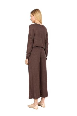 Woman wearing a brown outfit with wide-leg pants against a white background