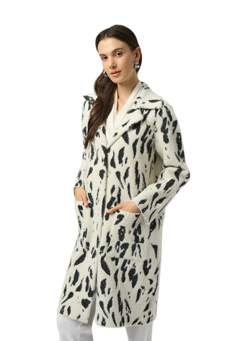 Woman wearing a long, patterned coat against a white background