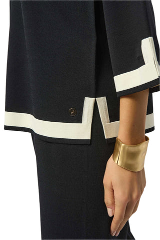 Black outfit with white trim and gold cuff on a plain background