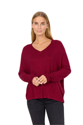 Woman wearing a burgundy sweater against a white background