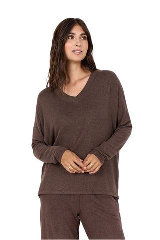 Woman wearing a brown long-sleeve top and pants against a white background