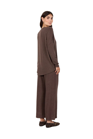 Woman wearing a brown outfit standing against a white wall
