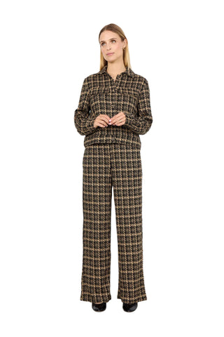 Woman wearing a houndstooth patterned outfit against a white background
