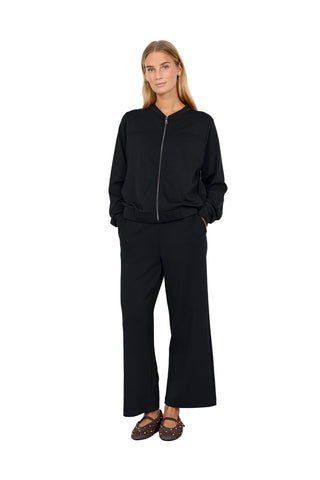Person wearing a black outfit standing against a white background