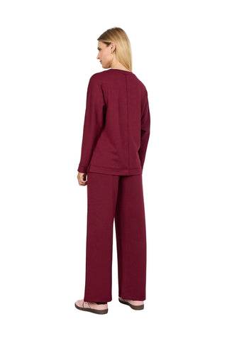 Woman wearing a burgundy outfit with wide-leg pants on a white background