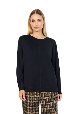 Woman wearing a black sweater and patterned pants on a white background