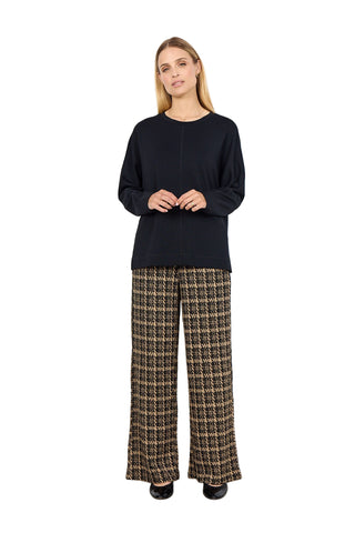 Woman wearing a black sweater and plaid pants against a white background