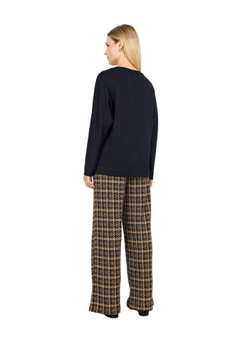 Person wearing a black sweater and plaid pants on a white background