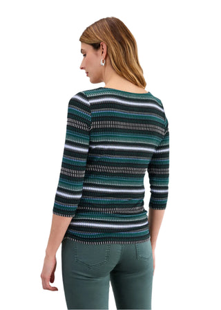 Woman wearing a striped sweater and green pants on a light gray background