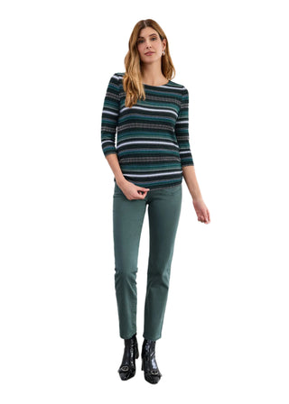 Woman wearing a striped sweater and green pants against a white background