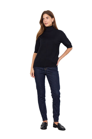 Woman wearing a black turtleneck and dark jeans on a white background