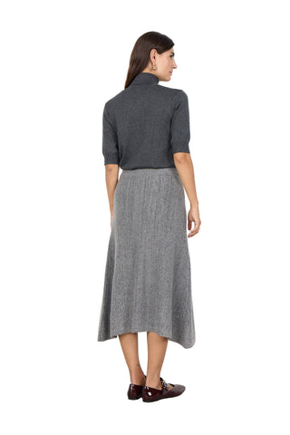Woman wearing a gray turtleneck and skirt against a white background