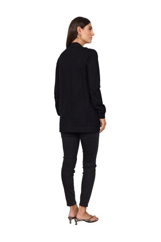 Woman wearing a black long-sleeve top and black pants against a white background