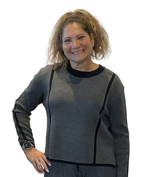Woman wearing a gray sweater with black accents against a white background