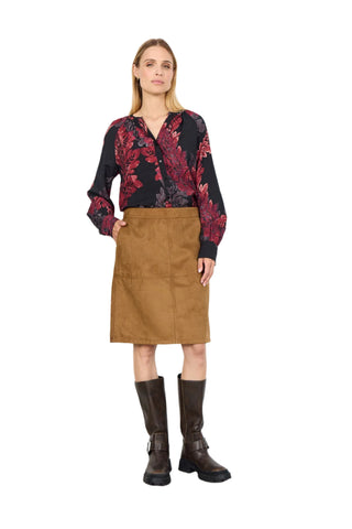 Woman wearing a floral blouse, brown skirt, and black boots on a white background