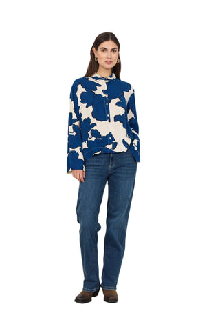 Woman wearing a blue and white floral sweater and jeans against a white background