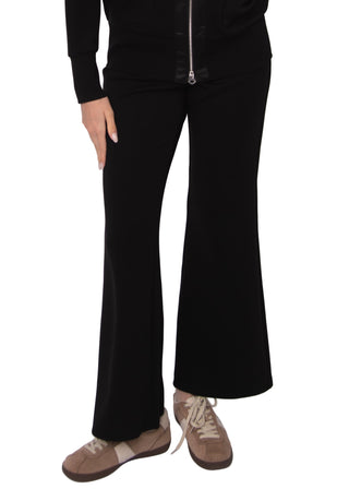 Person wearing black flared pants and brown shoes on a white background