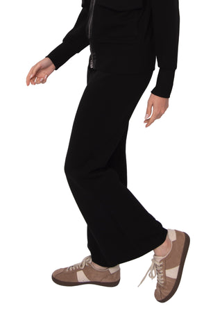 Person wearing black pants and brown shoes on a white background