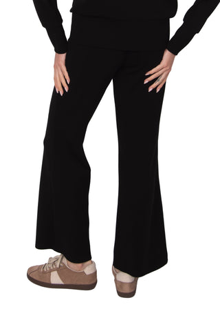 Person wearing black flared pants on a white background