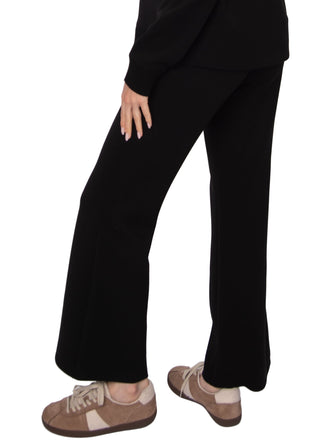 Person wearing black pants and brown shoes on a white background