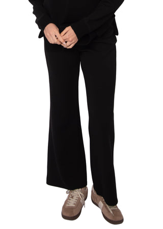 Person wearing black wide-leg pants and brown shoes on a white background