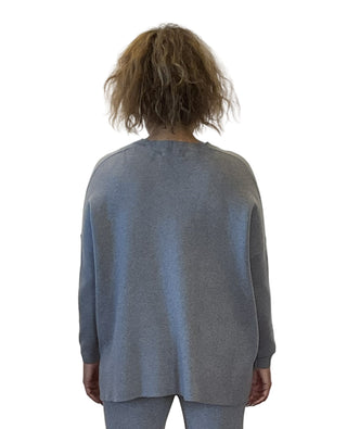 Person wearing a gray sweater and pants against a white background