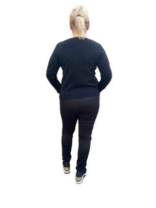 Person wearing a black outfit standing against a brick wall.