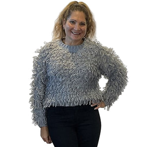 Woman wearing a textured gray sweater against a plain background