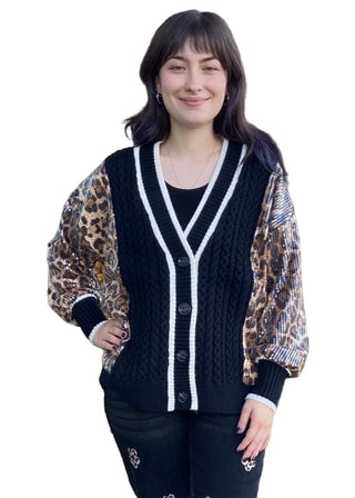 Woman wearing a black cardigan with white trim standing in front of a brick building.