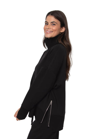 Woman wearing a black outfit with a zipper detail against a white background