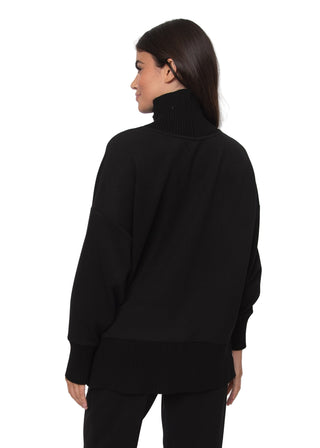 Person wearing a black turtleneck sweater against a white background