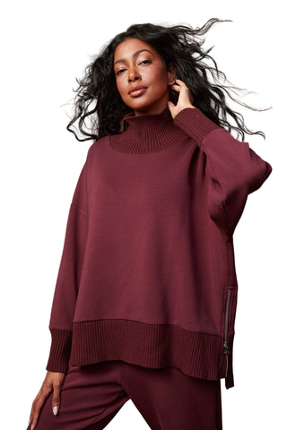 Woman wearing a burgundy sweater and pants against a brown background