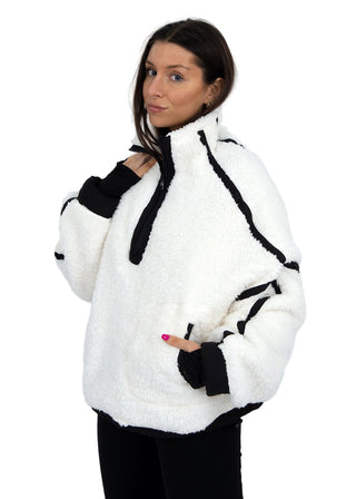 Woman wearing a white and black fleece jacket against a plain background