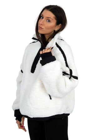 Woman wearing a white fleece jacket with black accents on a white background