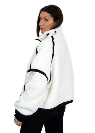 Person wearing a white and black textured jacket on a plain background