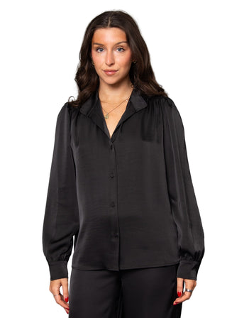 Woman wearing a black blouse against a gray background