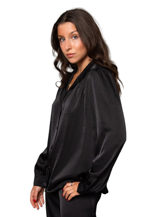 Woman wearing a black satin shirt against a gray background