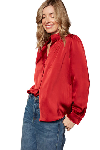 Woman wearing a red blouse and blue jeans against a brown background